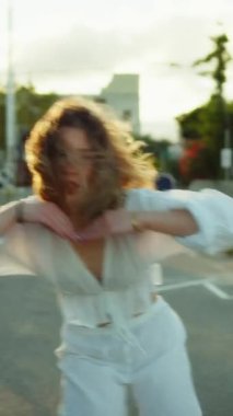 Yazın plajda beyazlar içinde dans eden genç bir kadın.