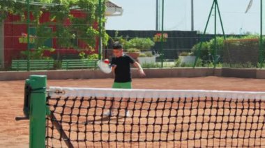 Bayan eğitmen, gündüz vakti Clay Court 'ta tenis öğretiyor..