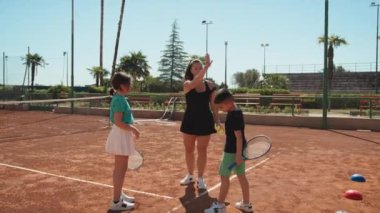 Bayan eğitmen, gündüz vakti Clay Court 'ta tenis öğretiyor..