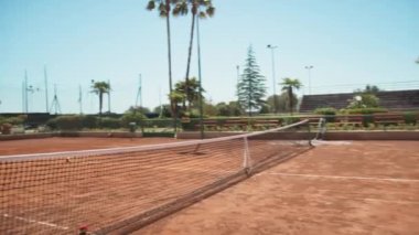 Bayan eğitmen, gündüz vakti Clay Court 'ta tenis öğretiyor..