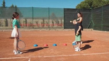 Bayan eğitmen, gündüz vakti Clay Court 'ta tenis öğretiyor..