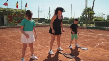 Bayan eğitmen, gündüz vakti Clay Court 'ta tenis öğretiyor..