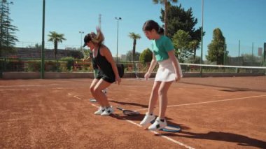 Bayan eğitmen, gündüz vakti Clay Court 'ta tenis öğretiyor..