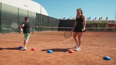 Bayan eğitmen, gündüz vakti Clay Court 'ta tenis öğretiyor..