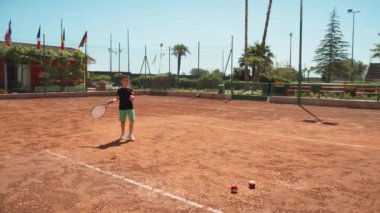 Bayan eğitmen, gündüz vakti Clay Court 'ta tenis öğretiyor..
