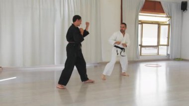 İki kıdemli karate uzmanı Kimono ile jimnastik yapıyor..