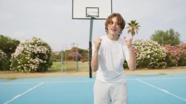 İki genç erkek dışarıda mavi alanda basketbol oynuyorlar..