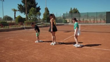 Bayan eğitmen, gündüz vakti Clay Court 'ta tenis öğretiyor..