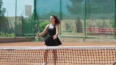 Bayan eğitmen, gündüz vakti Clay Court 'ta tenis öğretiyor..