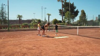 Bayan eğitmen, gündüz vakti Clay Court 'ta tenis öğretiyor..