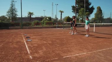 Bayan eğitmen, gündüz vakti Clay Court 'ta tenis öğretiyor..