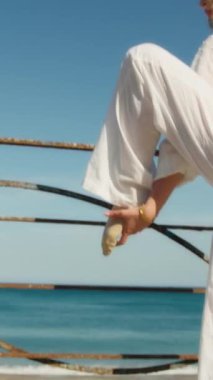 Yazın plajda beyazlar içinde dans eden genç bir kadın.