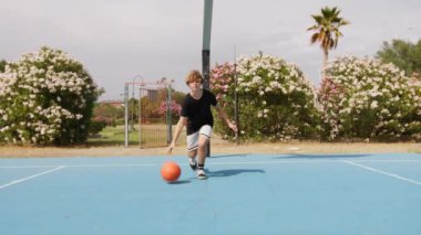 İki genç erkek dışarıda mavi alanda basketbol oynuyorlar..