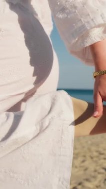 Yazın plajda beyazlar içinde dans eden genç bir kadın.