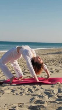 Yazın plajda beyazlar içinde dans eden genç bir kadın.