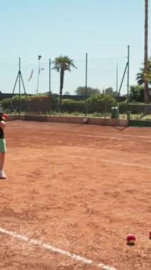 Bayan eğitmen, gündüz vakti Clay Court 'ta tenis öğretiyor..