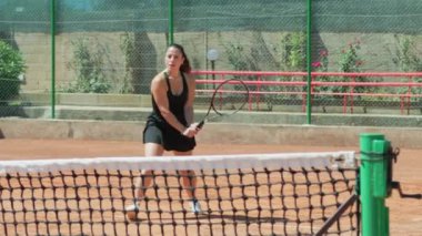 Bayan eğitmen, gündüz vakti Clay Court 'ta tenis öğretiyor..