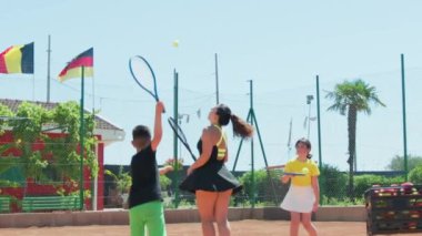 Bayan eğitmen, gündüz vakti Clay Court 'ta tenis öğretiyor..