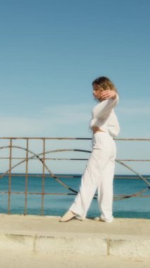 Yazın plajda beyazlar içinde dans eden genç bir kadın.