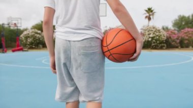 İki genç erkek dışarıda mavi alanda basketbol oynuyorlar..