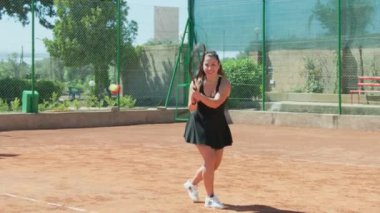 Bayan eğitmen, gündüz vakti Clay Court 'ta tenis öğretiyor..