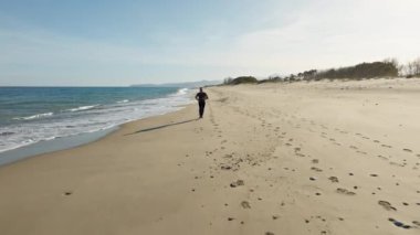 Sahilde okyanus suyunun yanında koşan adam sporu.