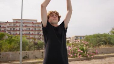 İki genç erkek dışarıda mavi alanda basketbol oynuyorlar..