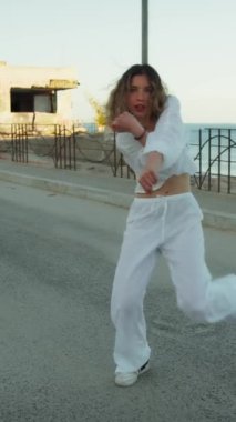 Yazın plajda beyazlar içinde dans eden genç bir kadın.