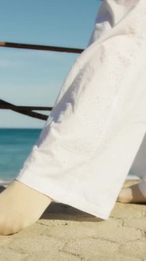 Yazın plajda beyazlar içinde dans eden genç bir kadın.