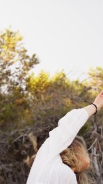 Yazın plajda beyazlar içinde dans eden genç bir kadın.