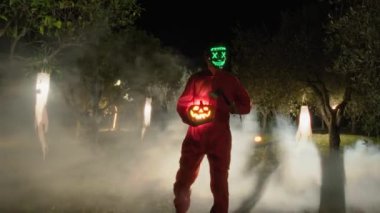 İsimsiz Maskeli Adam Geceleyin Sisli Ormanda Cadılar Bayramı Balkabağıyla Yürüyor.