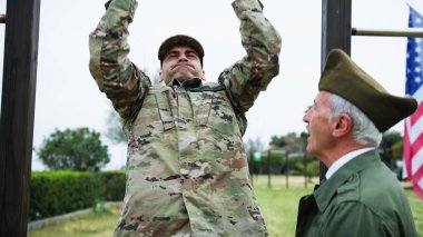 Yaşlı General, askeri öğrencinin fiziksel gücünü barfiks çekerek kontrol ediyor..