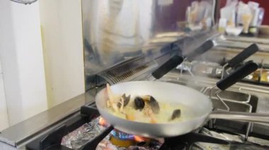 Şef deniz kenarında bir restoranda balık pişiriyor.