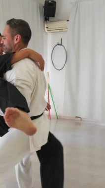 İki kıdemli karate uzmanı Kimono ile jimnastik yapıyor..