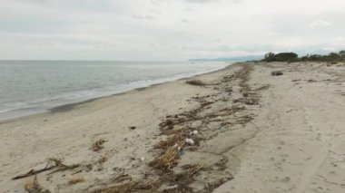 Çöp ve dallardan oluşan kirli kumsalda enkaz..