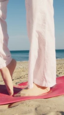 Yazın plajda beyazlar içinde dans eden genç bir kadın.