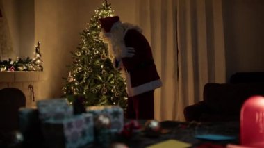 Noel Baba mektupları okuduktan sonra şöminenin başında kendini ısıtır.