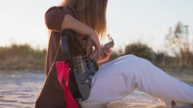 Sahilin yanındaki doğada bas gitar çalan bir kız..