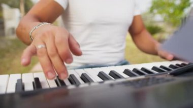 Beyaz gömlekli çocuk dışarıdaki doğada piyano çalıyor..