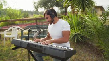 Beyaz gömlekli çocuk dışarıdaki doğada piyano çalıyor..