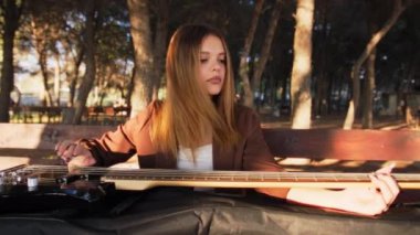 Sahilin yanındaki doğada bas gitar çalan bir kız..