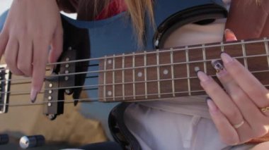 Sahilin yanındaki doğada bas gitar çalan bir kız..