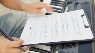 Beyaz gömlekli çocuk dışarıdaki doğada piyano çalıyor..