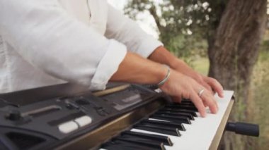 Beyaz gömlekli çocuk dışarıda klavye çalıyor..