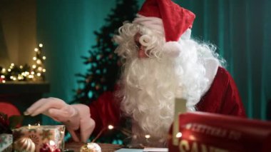 Noel Baba mektupları okuduktan sonra şöminenin başında kendini ısıtır.