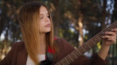 Sahilin yanındaki doğada bas gitar çalan bir kız..