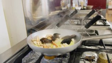 Şef deniz kenarında bir restoranda balık pişiriyor.