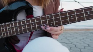 Sahilin yanındaki doğada bas gitar çalan bir kız..