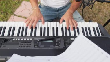 Beyaz gömlekli çocuk dışarıdaki doğada piyano çalıyor..