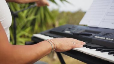 Beyaz gömlekli çocuk dışarıdaki doğada piyano çalıyor..